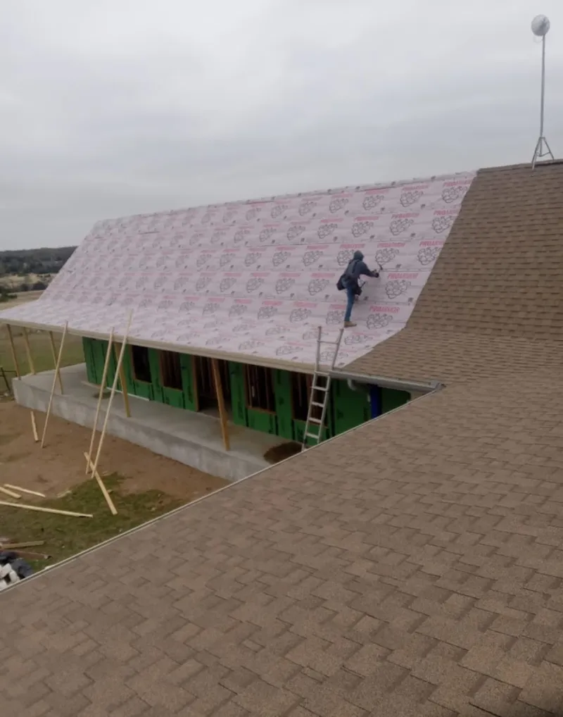 Worker preparing underlayment for a metal roof installation in Olive